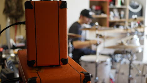 A-man-caucasian-drummer-in-a-garage-band-playing-his-instrument-with-guitar-amps-and-music-gear-SLOW-MOTION