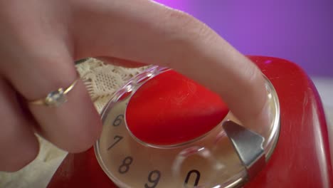 extreme close-up of a woman’s finger dialing a red rotary phone. the shot captures intricate details of the dial, lace cloth, and vintage textures, emphasizing a nostalgic and tactile retro mood