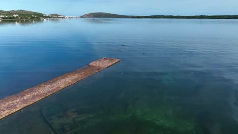 Small-old-brick-pier-floating-on-the-banks-of-Fornell's-Bay,-Menorca-Spain