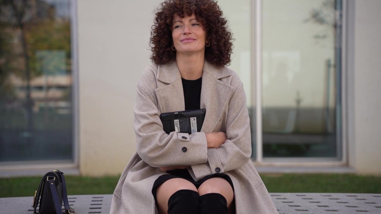 Una donna professionista seduta all'aperto in relax, intenta a usare il suo tablet oggi.
