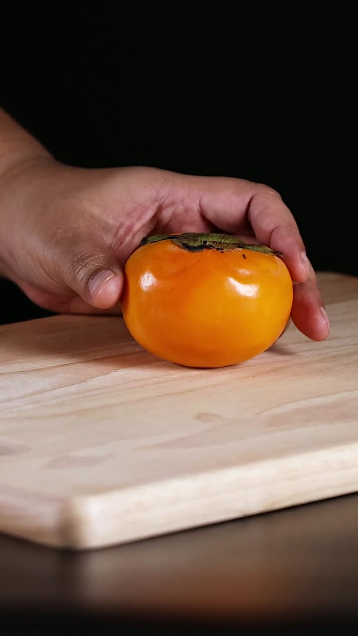 나무 절단판 에 손 으로 파시몬 을 놓는다