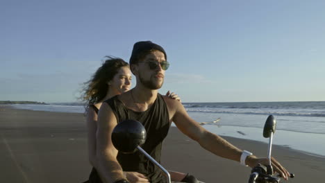 pareja montando una moto en la playa