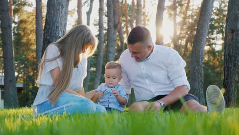 portrait of a young happy family mom dad and baby boy sitting on the lawn near his house at sunset s