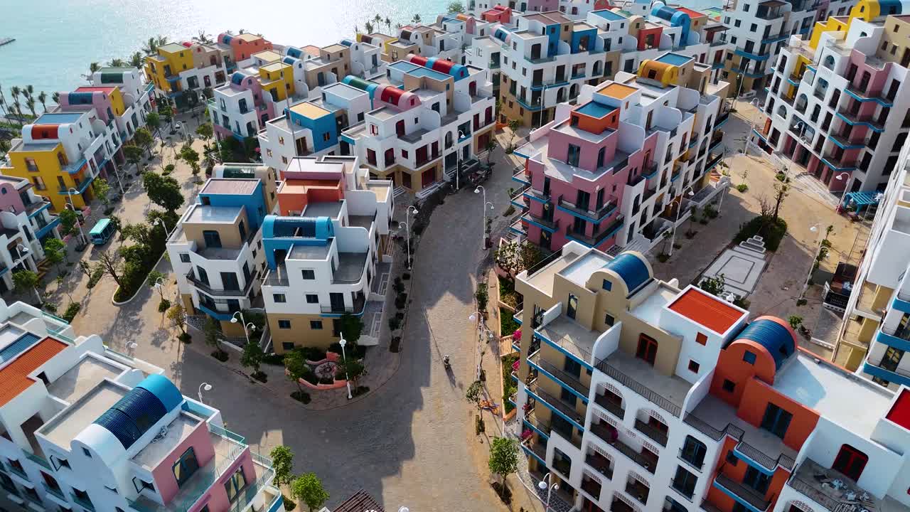 Colorful aerial view of Vinhomes project on Phu Quoc Island, Vietnam. Santorini-inspired architecture with bright facades, white buildings, blue domes, and scenic coastal surroundings.