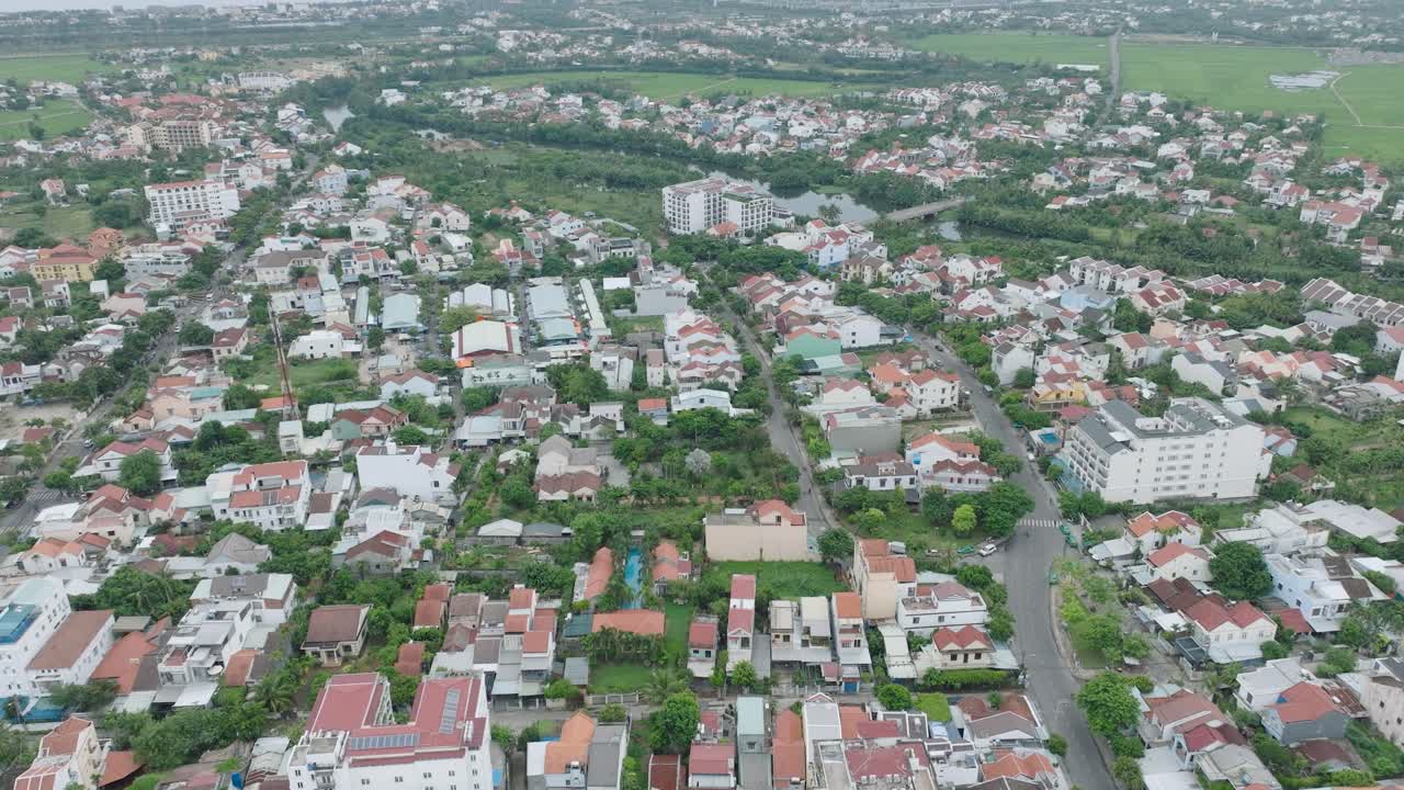 A residential area in hoi an, vietnam, showing rooftops and green spaces, aerial view