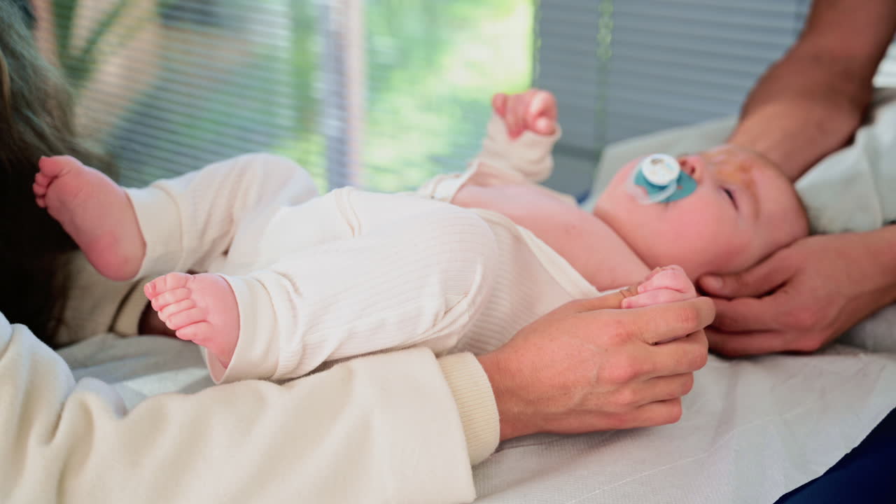Close up of a baby grasping an adult's fingers during a medical moment