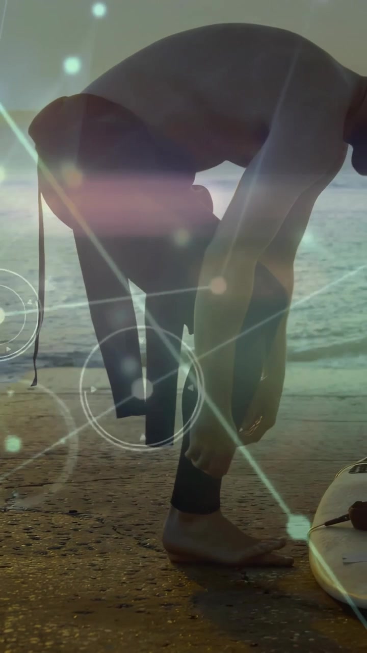Video verticale: Surfista che si infila la muta, allaccia il laccio, si prepara a surfare con bagliori di luce sul surfista.