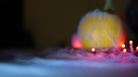 dry ice mist fog flowing from a pumpkin onto a flat surface, lights around the pumpkin