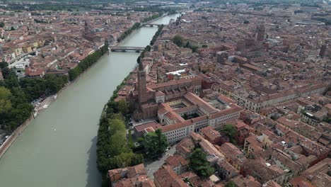 Toma-Aérea-De-La-Densa-Ciudad-De-Verona-Con-Arquitectura-Antigua-Y-Un-Río-Que-Fluye-En-El-Medio.