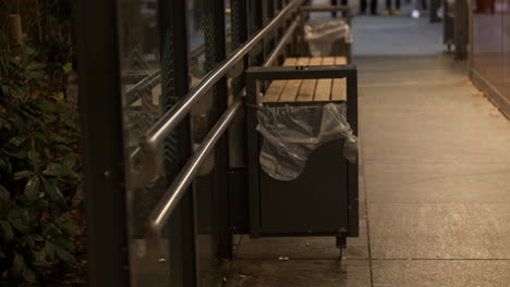 Static-shot-of-a-rat-looking-in-the-bin-standing-on-the-lip,-within-a-bus-shelter