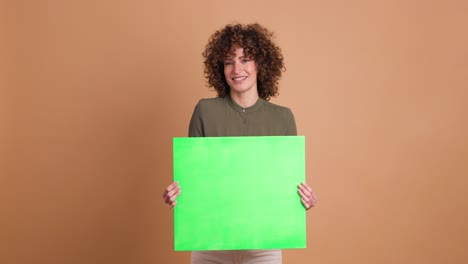 happy woman holding blank green paper in beige studio