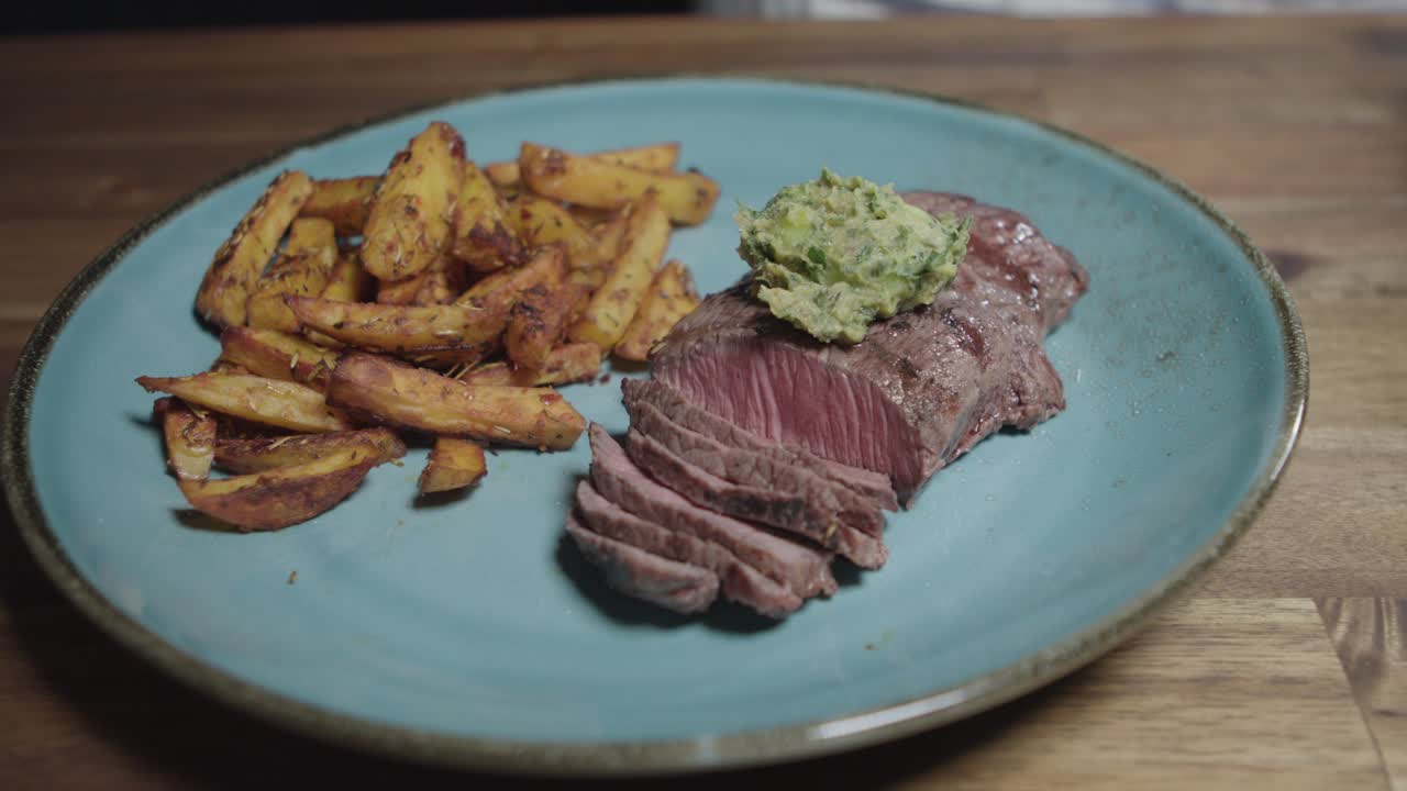 el chef pone mantequilla en rebanadas de carne en un plato, acompañado de papas fritas, comida argentina