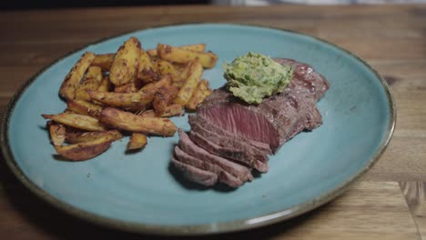 chef puts cafe en paris butter on slices of meat on a plate, accompanied by french fries, argentine food