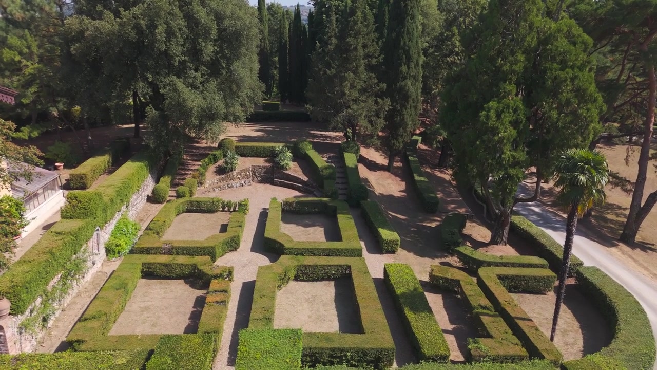 Veduta aerea di un giardino all'italiana formale con siepi geometriche e alberi maturi in estate
