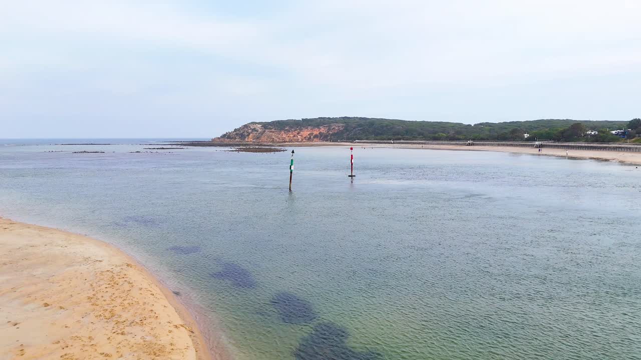 Aerial footage captures serene coastal landscape with calm waters and sandy shores at Barwon Heads, Victoria, under soft daylight
