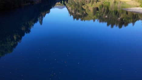 hermoso reflejo de la exuberante vegetación en el lago klamsee en austria - fotografía aérea de un dron