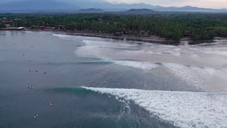 a drone view of the surf spot in la saladita, mexico. a perfect left hand break over a beautiful reef offers turquoise water and a quaint town in the background