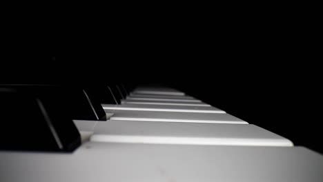 wide angle macro of electronic keyboard - static shot of keyboard and the song assist lighting the keys a red color, movement down and then pulling away from keys as song continues to play