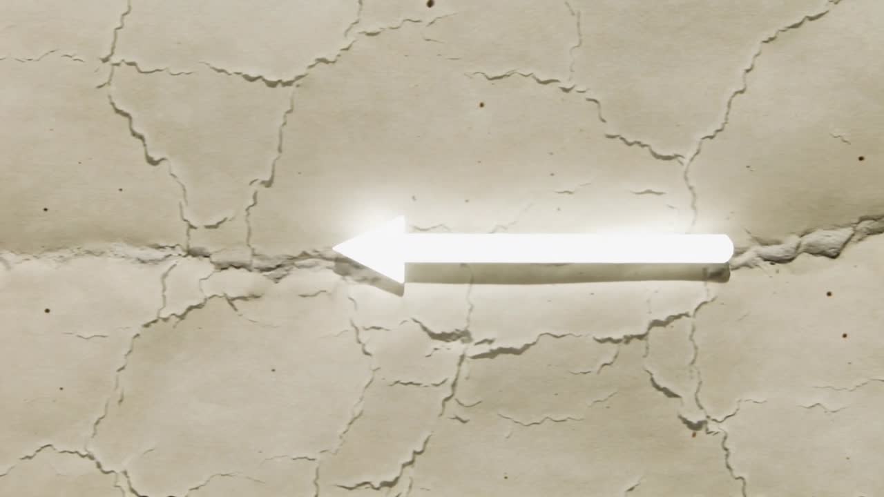 Pulsing white left arrow brightening while shimmer moving along shaft on cracked paper, halo specks