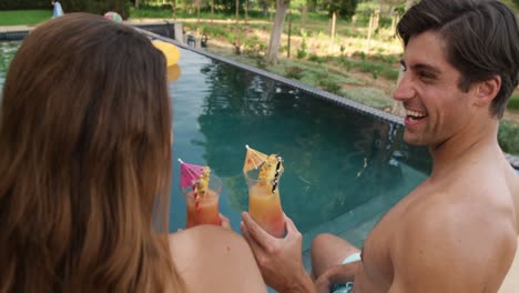 feliz pareja caucásica bebiendo cócteles durante un día soleado