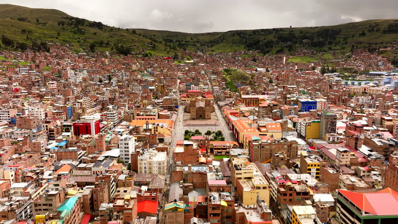 Catedral basílica de Puno rodeada de una ciudad densa en las tierras bajas del valle en un día nublado, órbita media aérea