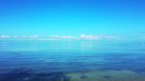 peaceful seascape with calm shallow lagoon where people swim and white clouds rising from horizon to bright blue sky in malaysia