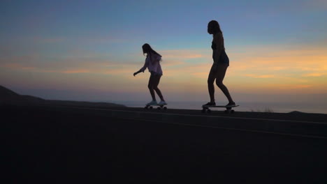 dos amigos patinan por una carretera al atardecer, sus movimientos capturados en cámara lenta, con el telón de fondo de las montañas y un cielo impresionante. llevan pantalones cortos