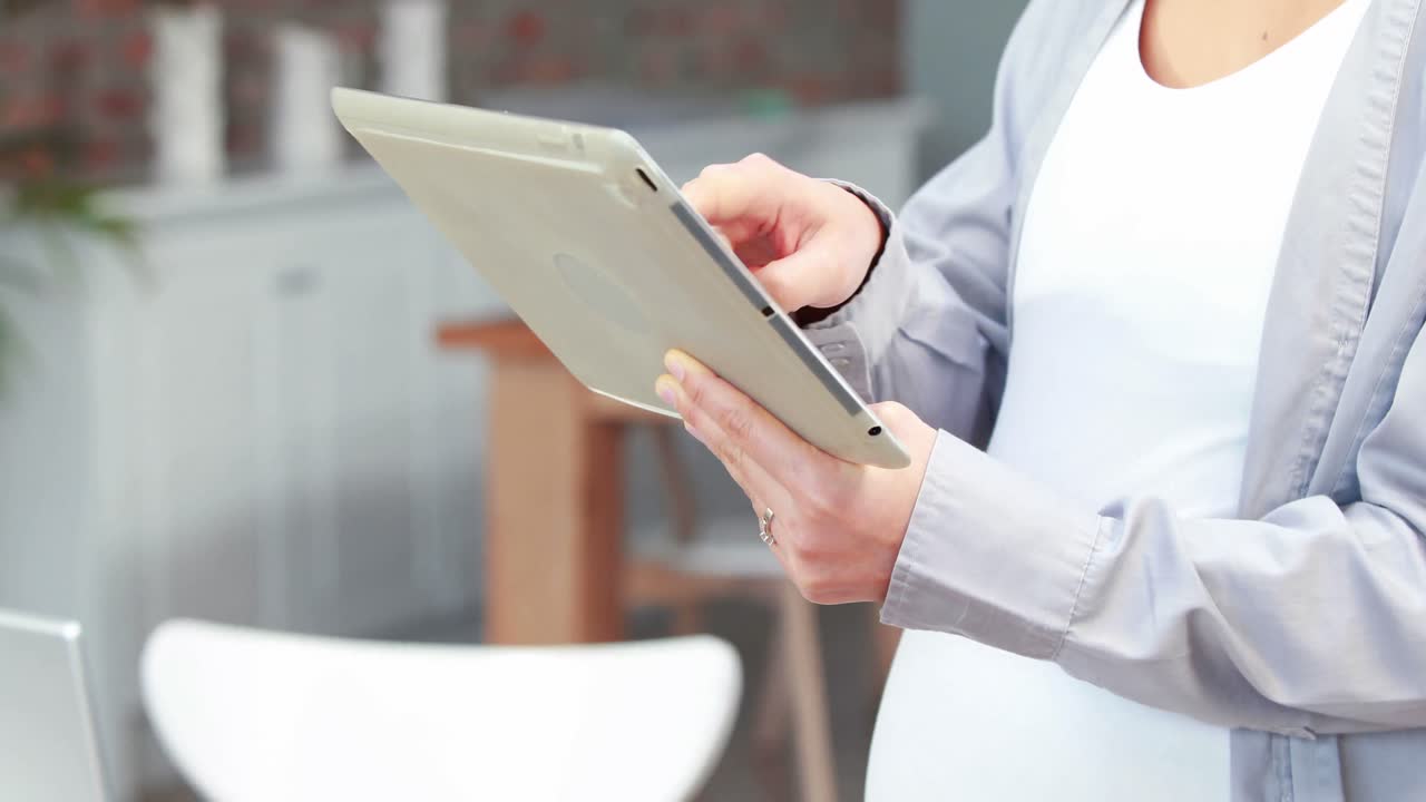 태블릿 pc를 사용하는 임신한 아시아 여성