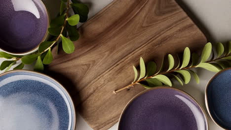 elegant ceramic plates with wooden board and greenery
