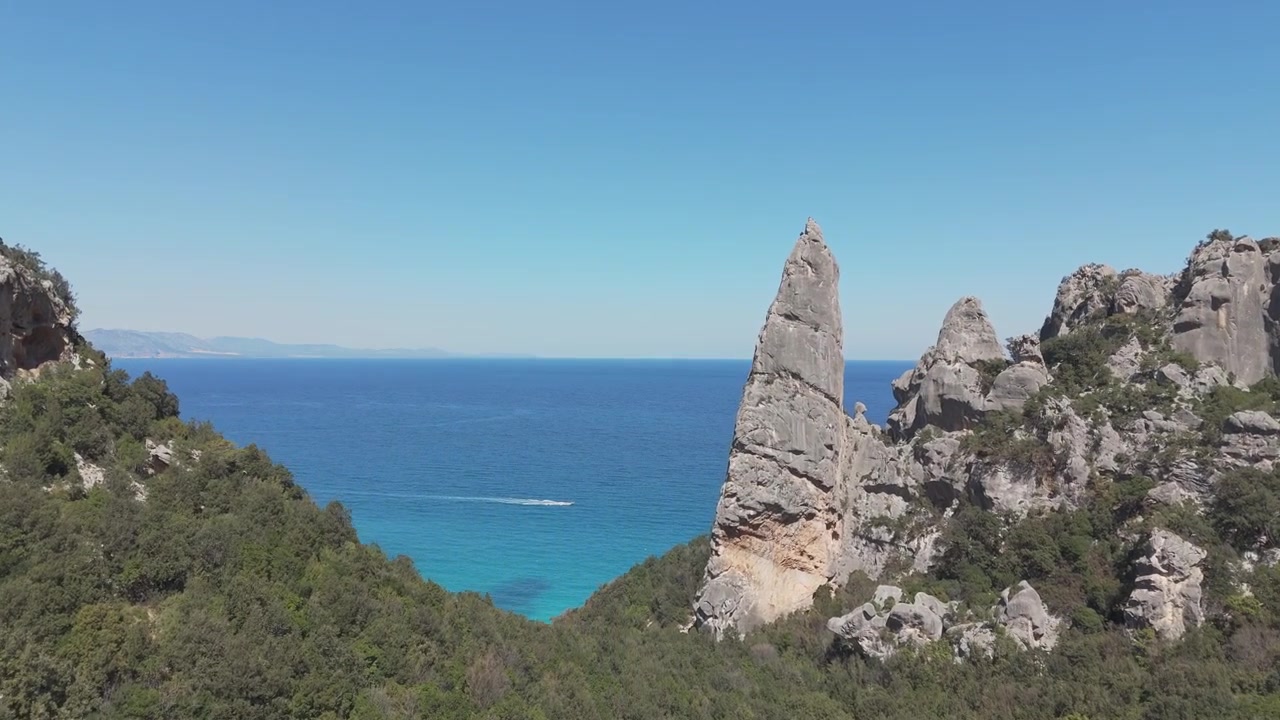 Pinnacolo calcareo vicino a Cala Goloritzé che si erge sopra le scogliere costiere a Baunei, Sardegna, cielo sereno, ripresa con drone.