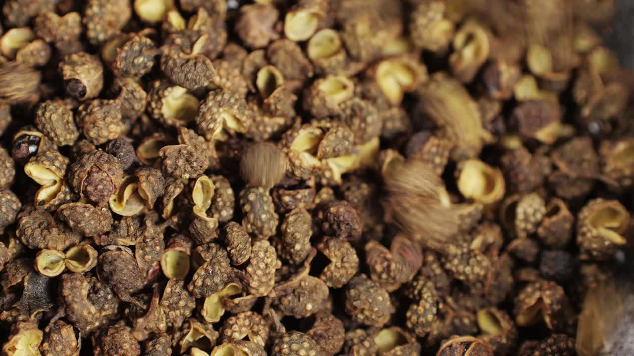 Dried black pepper falling down in grey plate top view. A bunch of natural black pepper peas hot spice.Seasonings and condiments concept