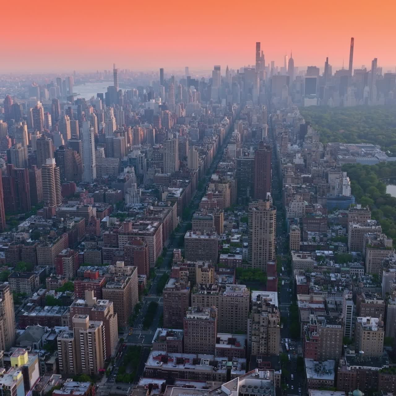 Vast New York panorama at sun down. Park with a pond in the downtown. Metropolis at backdrop of pink skies