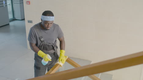 top view of cleaning man cleaning stair railing inside an office building