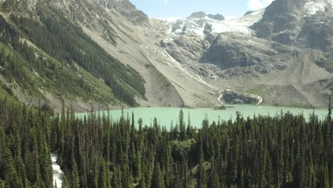 Joffre-Lakes-in-BC-Canada,-Drone-shot-of-trees-and-turquoise-lake-with-the-glacier-on-the-background,-British-Columbia,-Canada-in-4K