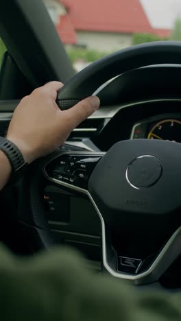 close up view of a driver's hand on the steering wheel of a car