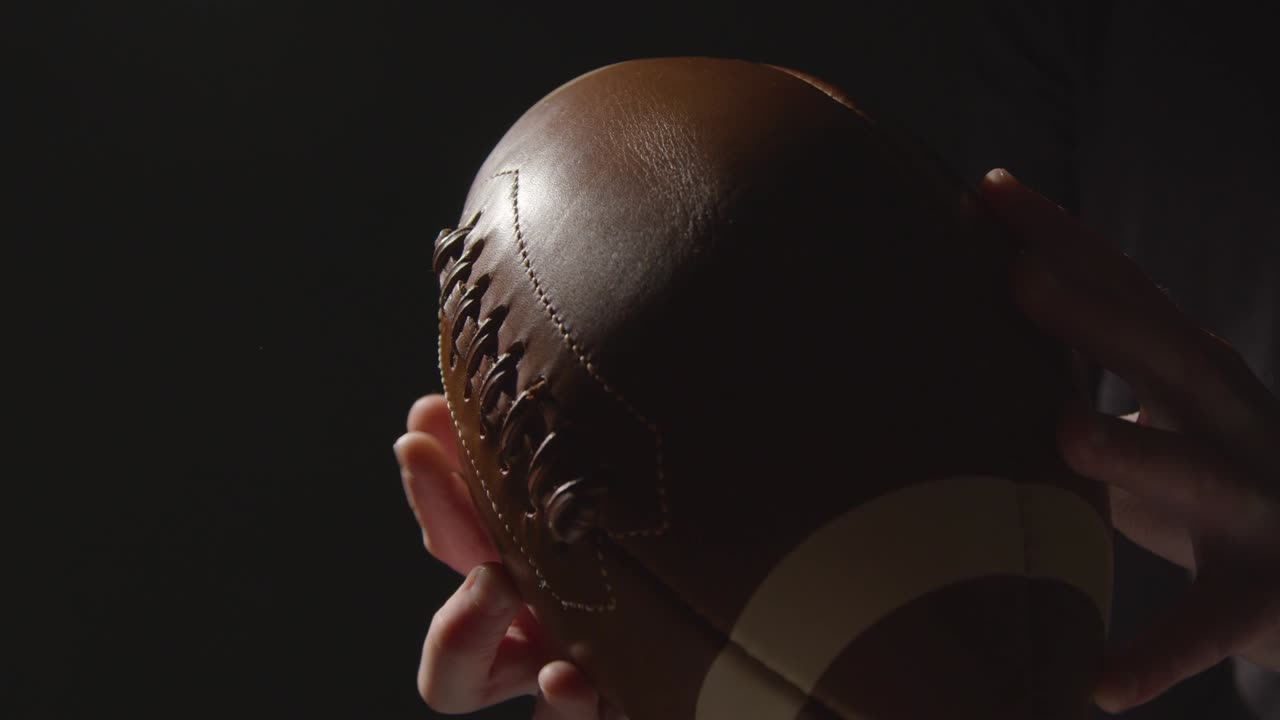 Close Up Studio Shot Of American Football Player Holding Ball With Low Key Lighting 4