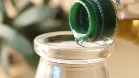 pouring olive oil from a bottle into a glass