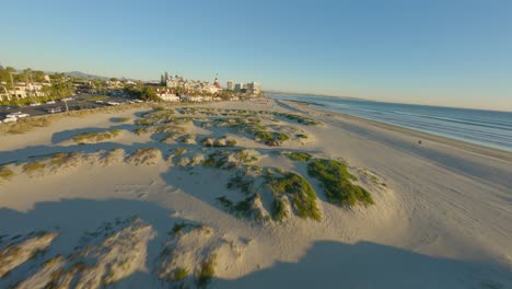 aerial fpv shot of a beach landscape during sunset near hotel resorts