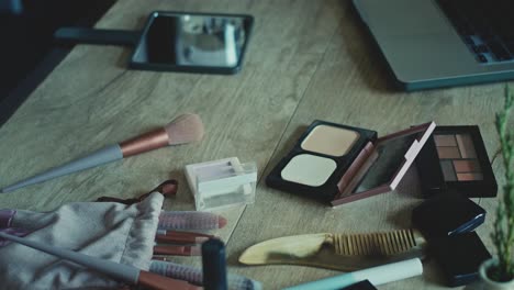 makeup and beauty products on a wooden table with a laptop