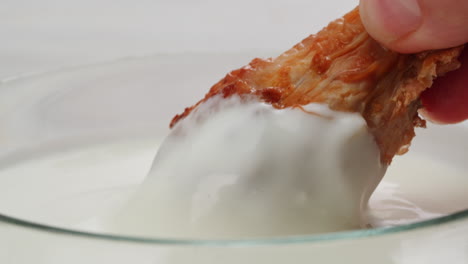 dipping a fried chicken wing in sauce