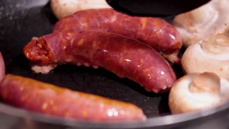 sausages and mushrooms frying in a pan