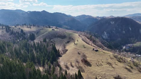 colinas onduladas y árboles esparcidos bajo un cielo despejado, con cadenas montañosas en el fondo