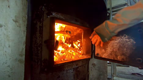 hombre en cámara lenta arrojando leña a un horno 3