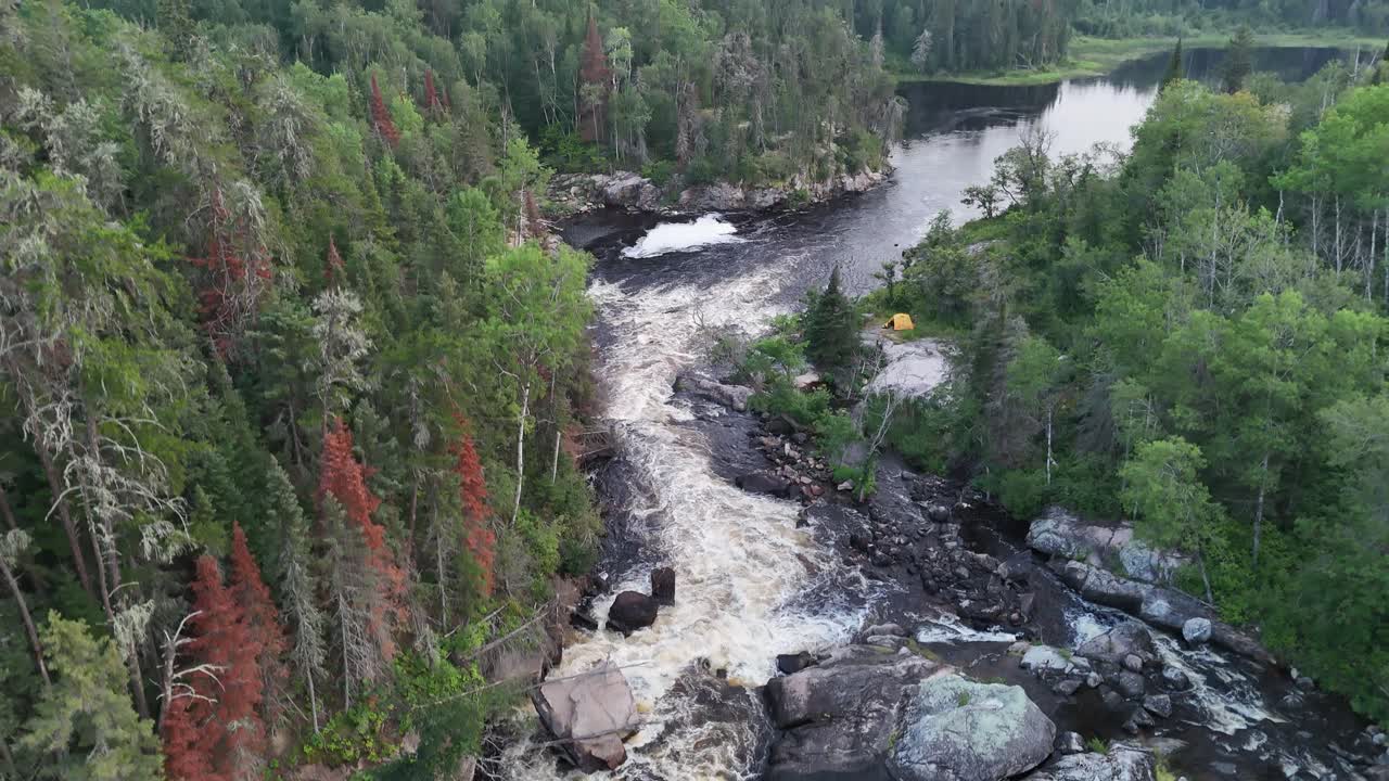 Turtle Falls Manigotagan-joella Manitobassa virtaa Kanadan kilven graniitin yli. Ilmakamera nousee koskien yläpuolelle paljastaen boreaalisen metsän ja yhden joenrantateltan putousten vieressä.