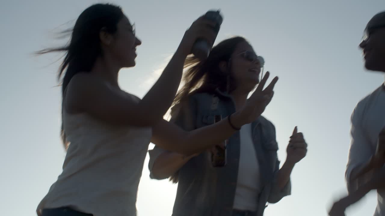 해가 지는 동안 춤을 추는 젊은이들의 그룹.