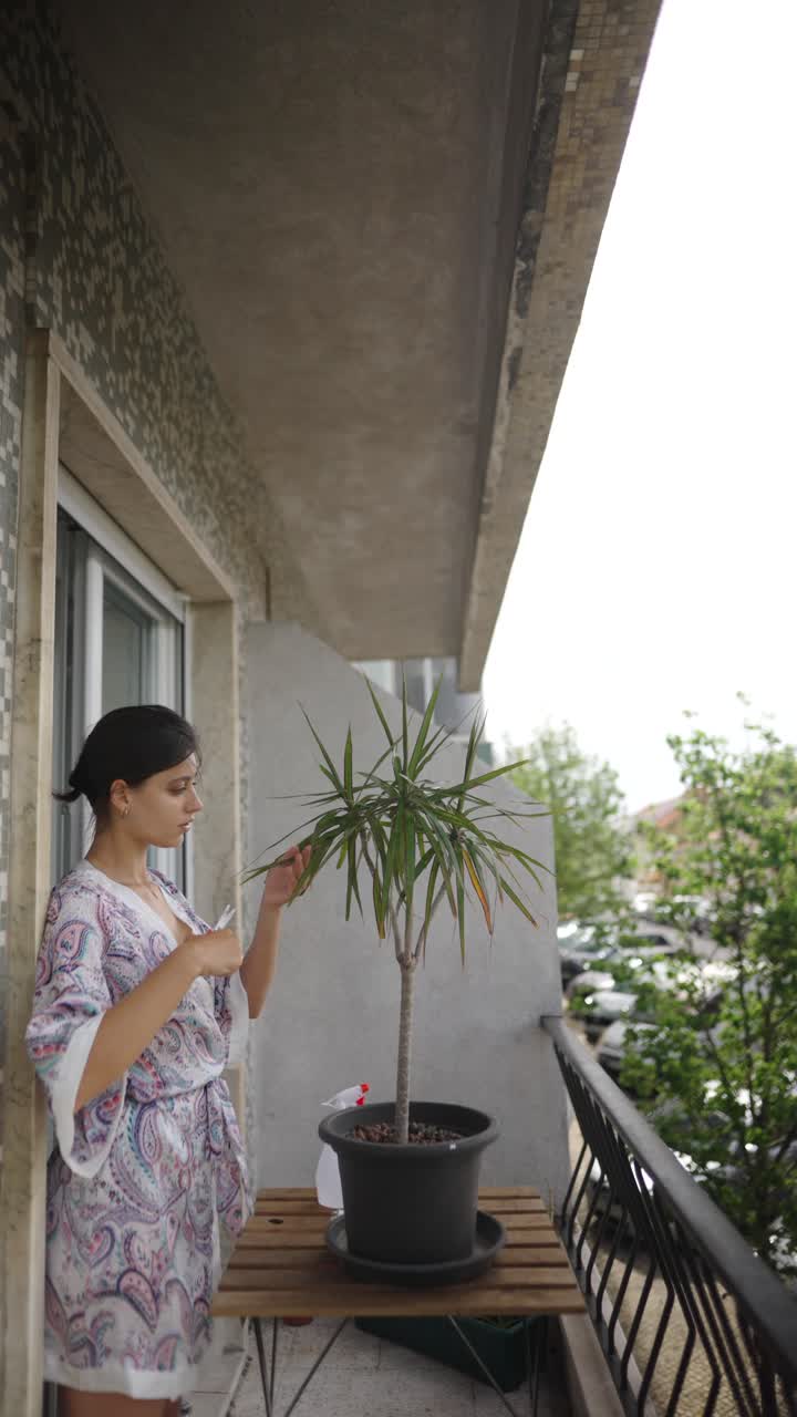 Woman watering a plant on a balcony