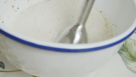 revolviendo la leche con una batidora dentro de un plato hondo blanco
