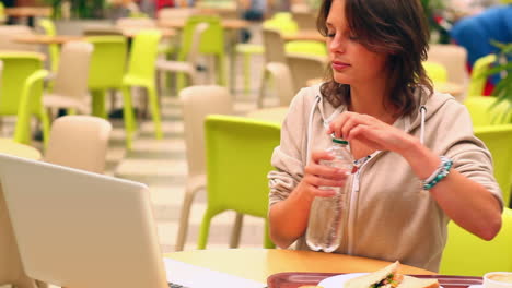 estudiante morena estudiando y bebiendo agua en la cantina