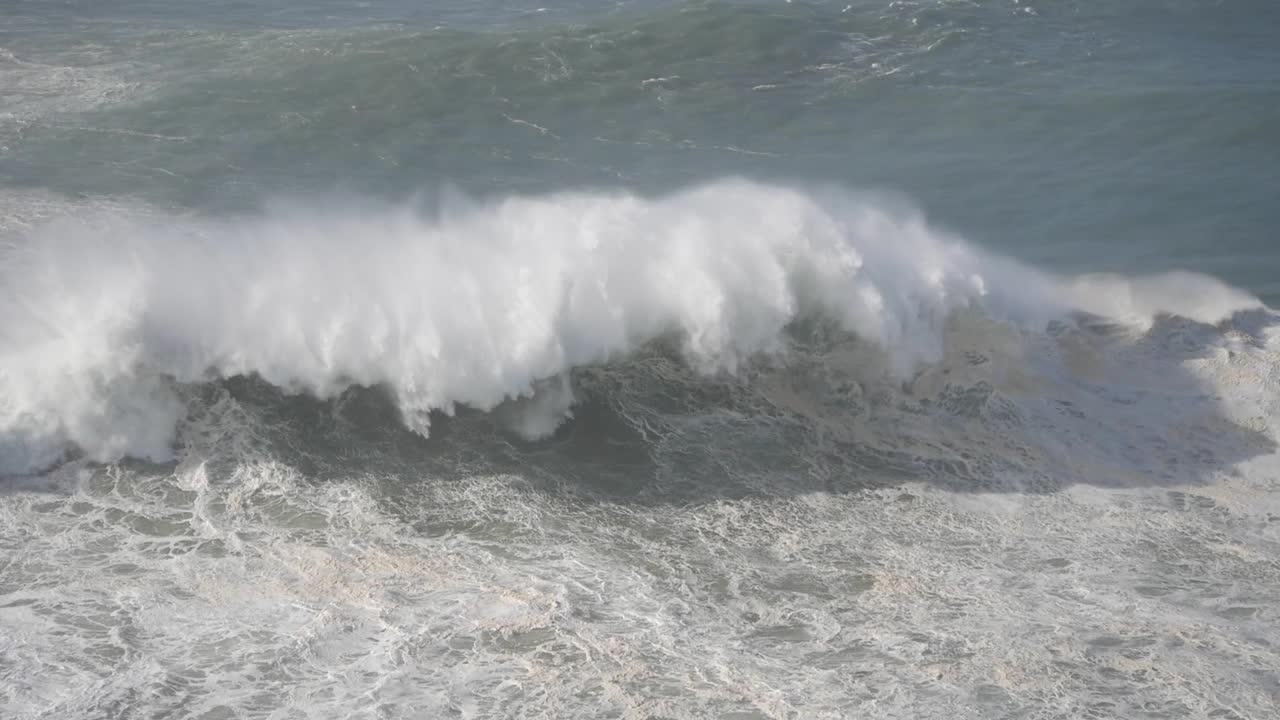 Powerful waves crashing along the shore at Nazaré, Portugal, showcasing the ocean's force