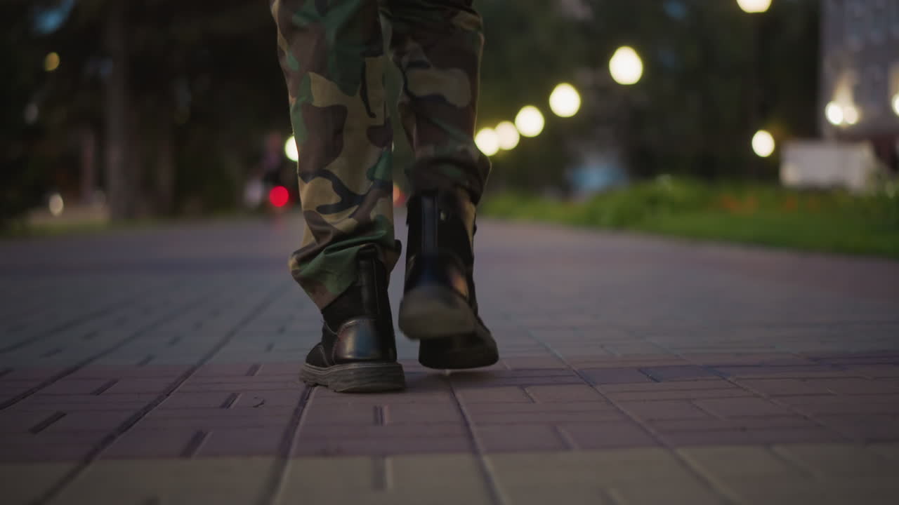 Calzature militari per la città di notte, stivali tattici in pelle che attraversano ritmicamente le vie urbane, soldati in stivali tattici che marciano ritmicamente per le strade della città di notte, vivendo il movimento urbano